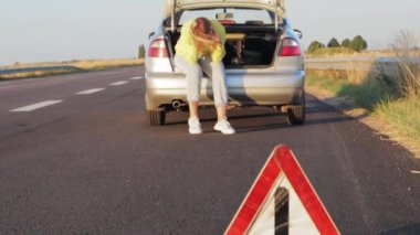 Kız arabanın bagaj bölümünde oturuyor ve en stresli kızın içinde telefonun yanından geçiyor. Ön tarafta acil servis işareti var. Yüksek kalite 4k görüntü