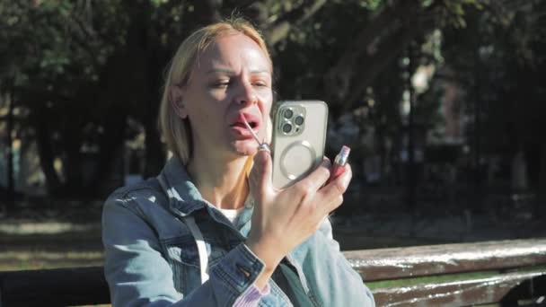 Pretty Girl Painting Her Lips Using Smartphone Mirror Outdoors High — Stock Video
