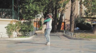 Oğlunu kaldıran ve döndüren bir adamın yan görüntüsü. Çocuk parkta babasına sarılıyor. Aile kavramı. Yüksek kaliteli FullHD görüntüler