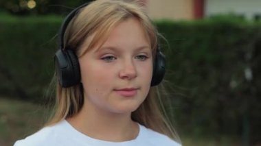Güzel görünümlü genç bir kızın portresi kulaklıkla şarkı söyleyen, siyah kulaklıklar takan ve müzik dinleyen, kulaklık takan bir kız. Yüksek kalite 4k görüntü