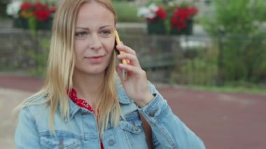 Şehrin dışında dikilen neşeli bir bayanın portresi ve cep telefonuyla gülüp eğlenen sohbetler. İnsanlar ve iletişim konsepti. Yüksek kalite 4k görüntü