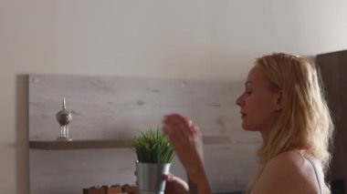 Güzel bir kız tozu kaldırır ve çiçekleri raflara koyar. İskandinav tarzı. Yapay çiçeklerle ilgilenmek. Parlak bir iç mekan. Yüksek kalite 4k görüntü