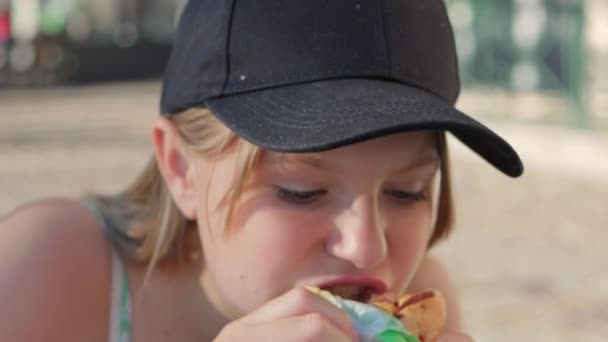 黒い帽子に軽い光の女の子が 通りでスナックを食べて 子供の顔を閉じた 高品質の4K映像 — ストック動画