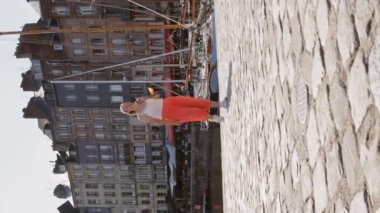 İskelede yürüyen pembe etekli sarışın bir kızın dikey videosu. Yüksek kalite 4k görüntü