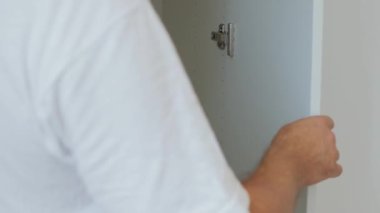İş üniformalı bir erkek gardırop monte ederek rafları birleştiriyor. Mobilya montaj hizmeti konsepti. Tüm ticaret malzemeleri dolabının erkeği. Yüksek kalite 4k görüntü