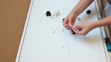 Utangaç genç bir kadın odada mobilyaları kendi başına monte etmeye çalışıyor. Kız çarşaf dolabını kendisi monte etmek istiyor. Yüksek kalite 4k görüntü