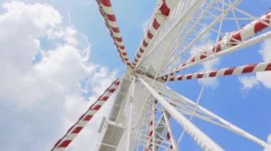 Büyük, uzun, beyaz dönme dolabın geniş açılı görüntüsü kusursuz mavi gökyüzüne karşı. Mutlu bir yaz tatili hissi. Yüksek kalite 4k görüntü