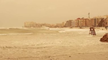 Kum fırtınası ve güçlü rüzgar bir İspanyol tatil köyünde, deniz kıyısında. Yüksek kalite 4k görüntü