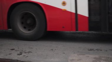 Bir Avrupa şehrinde bir toplu taşıma otobüsü yol boyunca seyahat eder. Tekerlek lastiklerini yavaş çekimde yakın çekim. Yüksek kaliteli FullHD görüntüler