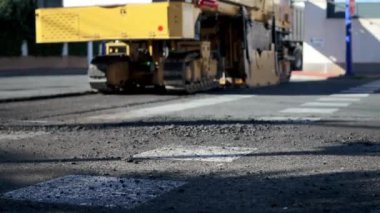 Asfalt değirmen makinesi ya da soğuk düzlem, asfalt tabakasını sokaktan turuncu kamyon gövdesine çıkarır. Yumuşak odaklanma. Gerçek zamanlı video. Yol yapımı teması. Yüksek kaliteli FullHD görüntüler