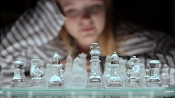 チェスを演じる劇的な夜 背景にある女の子は どのように行動するかを考えています ガラスのチェスをする 高品質の4K映像 — ストック動画