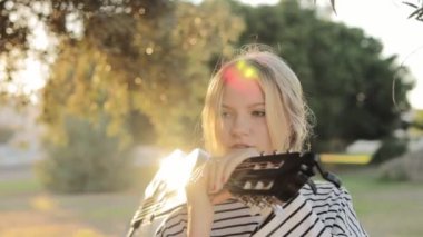 Parkta burnunda piercingle dolaşan, omzunda siyah bir gitarla gezen hafif görünümlü bir hipster kız. Video bir gencin etrafında çekildi. Yüksek kaliteli FullHD görüntüler