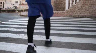 Spor giyimli genç bir çocuk yaya geçidinde karşıdan karşıya geçiyor, çocuk elinde bir basketbol topu tutuyor. Yüksek kalite 4k görüntü