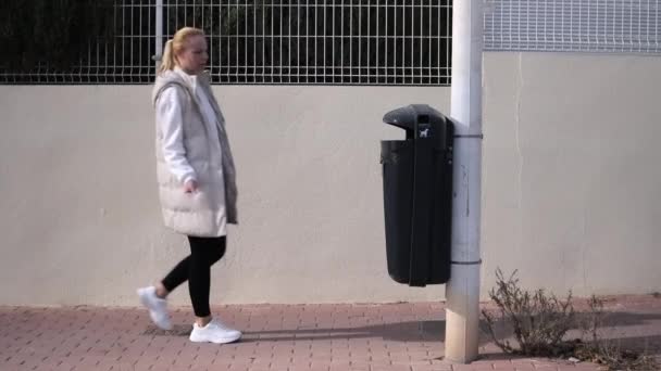 Eine Junge Frau Wirft Müll Einen Mülleimer Während Sie Eine — Stockvideo