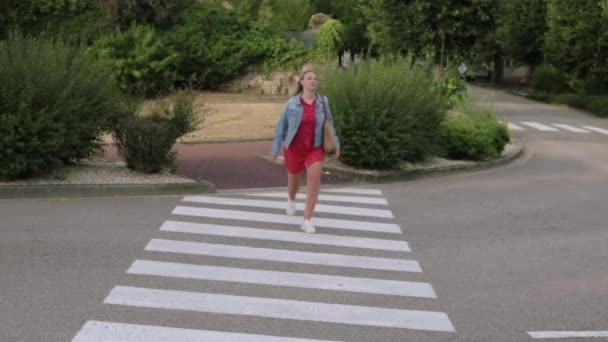赤いドレスウォークで若い美しい少女モデルビジネス女性の学生 ジャンプ 道路上の街を横断歩行者に沿って円 歩行者横断 高品質フルHd映像 — ストック動画