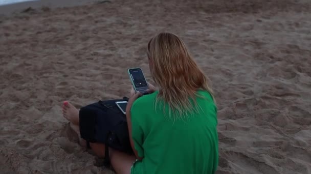 Kız Kameraya Arkasını Döner Yeşil Bir Tişörtle Kumsalda Oturur Telefona — Stok video