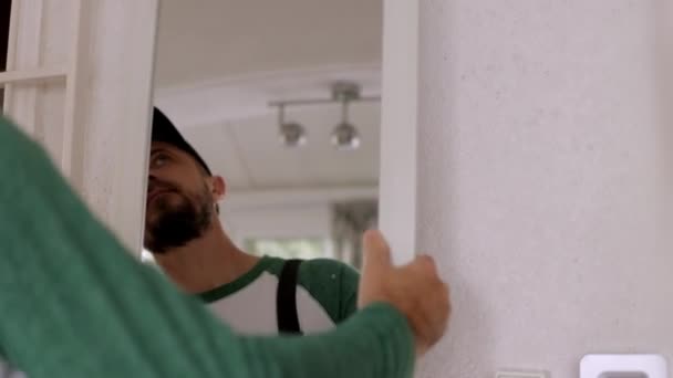 Молодой Человек Комбинезоне Устанавливает Зеркало Стене Комнаты Высококачественные Кадры — стоковое видео