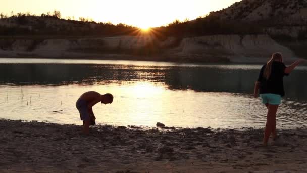 Zwei Kinder Spielen Mit Wasser Ufer Des Bergsees Bei Sonnenuntergang — Stockvideo