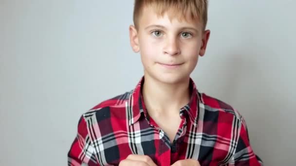 一个快乐的欧洲少年把一件红色格子衬衫扣上了纽扣 白色的背景是一个男孩的肖像 高质量的4K镜头 — 图库视频影像