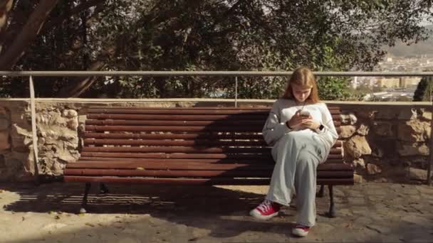 Ein Schöner Blonder Teenager Sitzt Auf Einer Bank Stadtpark Benutzt — Stockvideo