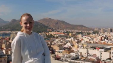 Mutlu turist kız şehrin manzarasına hayran kalıyor, kamera kıza yaklaşıyor. Yüksek kalite 4k görüntü