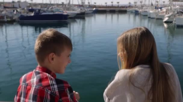 一个男孩和一个女孩一起坐在游艇门的后面 哥哥和姐姐背对着摄像机 兴高采烈地交谈着 高质量的4K镜头 — 图库视频影像