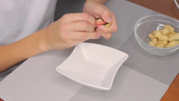땅콩이나 호두를 테이블에 앉아있는 땅콩을 껍질을 벗기는 고품질 Fullhd — 비디오