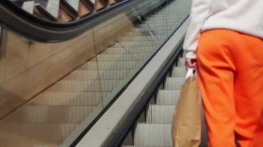 Yürüyen merdivenin korkuluğunu tutan genç bir kadının yakın çekimi. Bir kız alışveriş merkezinde yürüyen merdivene çıkıyor. Yüksek kaliteli FullHD görüntüler