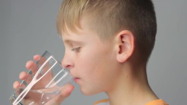 Netter Junge Trinkt Sauberes Wasser Aus Einem Glas Auf Grauem — Stockvideo