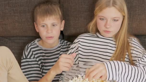 Дети Сидят Диване Гостиной Едят Попкорн Смотрят Телевизор Вместе Выходные — стоковое видео