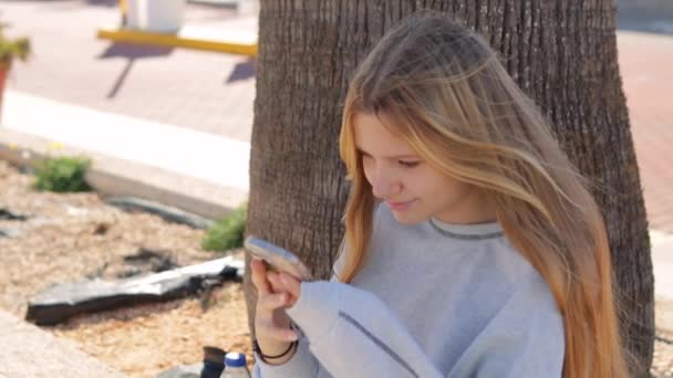 Genç Bir Kız Parkta Oturuyor Elinde Bir Telefon Tutuyor Bir — Stok video