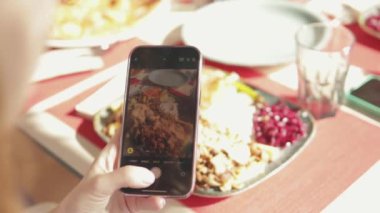 Sosyal medya kaynaklarına fotoğraf çekmek için dijital cep telefonu kamerasıyla yemek çeken bir kadının üst görüntüsünü kapatın. Kızarmış patates, yeşil salata ve ızgara et yiyen bir kadın.
