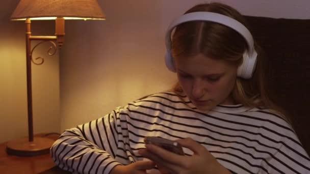 Nastolatka Swetrze Paski Siedząca Kanapie Słuchająca Muzyki Słuchawkach Telefonem Rękach — Wideo stockowe