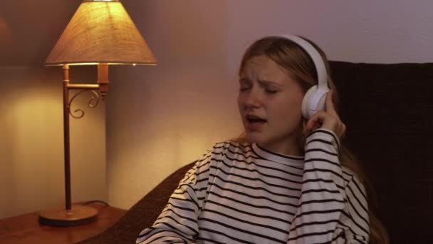 Egy Tinédzser Lány Csíkos Pulcsiba Öltözve Kényelmesen Kanapén Elmerül Zenéjében — Stock videók