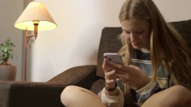 Sosyal medyayı taramak için cep telefonu kullanan güzel bir kızın videosunu kapat. İnternetten alışveriş yapan gülümseyen genç bir kız. İnternetten mal sipariş eden, video izleyen. Yüksek kalite FullHD