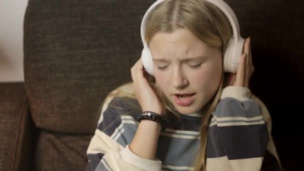 ソファーに座って 鼻のピアスを持つヒップスターの少女は 彼女のヘッドフォンを通して音楽を楽しんで スタイルと味で彼女の個性を表現しています 高品質のフルHd映像 — ストック動画