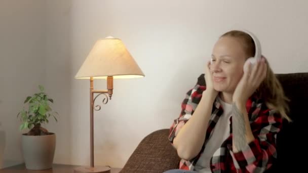 Egy Lány Kanapén Fehér Fülhallgatót Visel Elveszve Zenében Ami Átáramlik — Stock videók