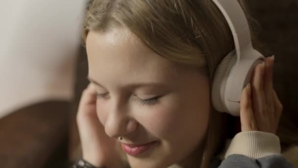 ソファーに座って 鼻のピアスを持つヒップスターの少女は 彼女のヘッドフォンを通して音楽を楽しんで スタイルと味で彼女の個性を表現しています 高品質のフルHd映像 — ストック動画