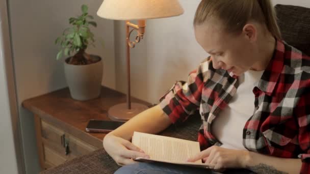 Flicka Klädd Röd Skjorta Och Jeans Sitter Vardagsrummet Nedsänkt Bok — Stockvideo