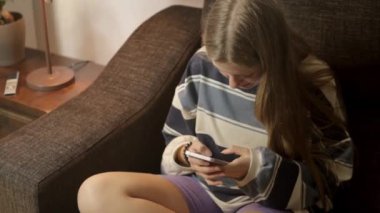 Sosyal medyayı taramak için cep telefonu kullanan güzel bir kızın videosunu kapat. İnternetten alışveriş yapan gülümseyen genç bir kız. İnternetten mal sipariş eden, video izleyen. Yüksek kalite FullHD