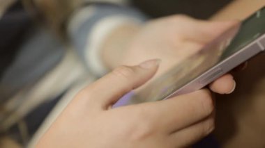 Kamera, bir kızın ellerine yakından odaklanıyor. Parmakları, cihaza bağlanırken telefonu nazikçe tutuyor. Yüksek kaliteli FullHD görüntüler