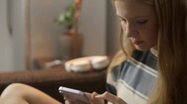 Hipster bir kız bir odada oturur, telefonunu bir kenara bırakır ve bir kitap alır. Video yandan çekiliyor, dijital etkileşimden analog etkileşime geçişi yakalıyor, Yüksek kalite