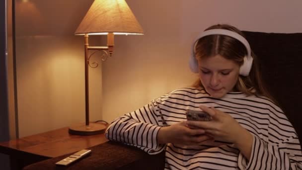 Μια Έφηβη Ντυμένη Ριγέ Πουλόβερ Κάθεται Άνετα Στον Καναπέ Βυθισμένη — Αρχείο Βίντεο