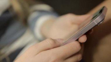 Kamera iyice yakınlaşıyor, kız telefonu sıkıca tutarken ellerinin detaylı bir görüntüsünü yakalıyor, belki yoğun bir konsantrasyon ya da iletişim anına bağlanıyor. Yüksek kalite