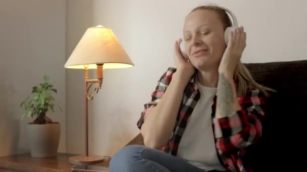 Lány Kanapén Fehér Fejhallgatót Visel Miközben Élvezi Zenét Elveszve Ritmusban — Stock videók