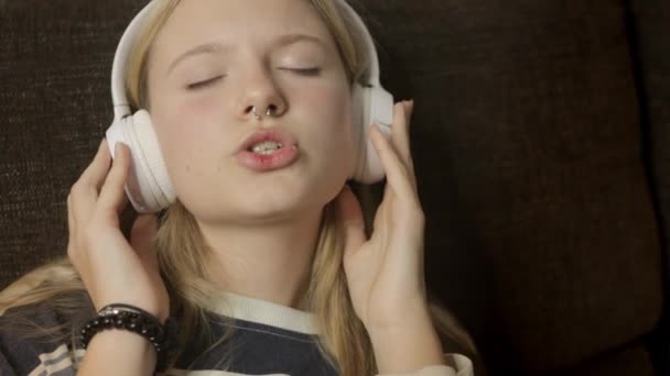 Ένα Κορίτσι Που Φοράει Λευκά Ακουστικά Ακούει Μουσική Και Τραγουδά — Αρχείο Βίντεο