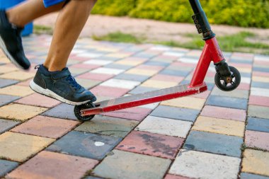 Parkta scooterlı bir çocuk, ayaklarına yakın çekim ve scooter, açık hava eğlencesi ve çocukluk maceraları..