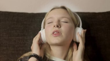 Evde kulaklıkla müzik dinleyen genç bir kadın.