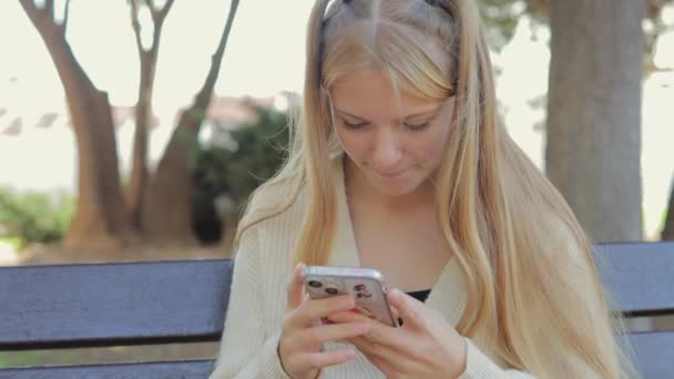 Girl White Shirt Sits Bench Uses Smartphone Typing Park — Stock Video