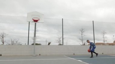 Basketbol sahasında basketbol oynayan iki genç adam.